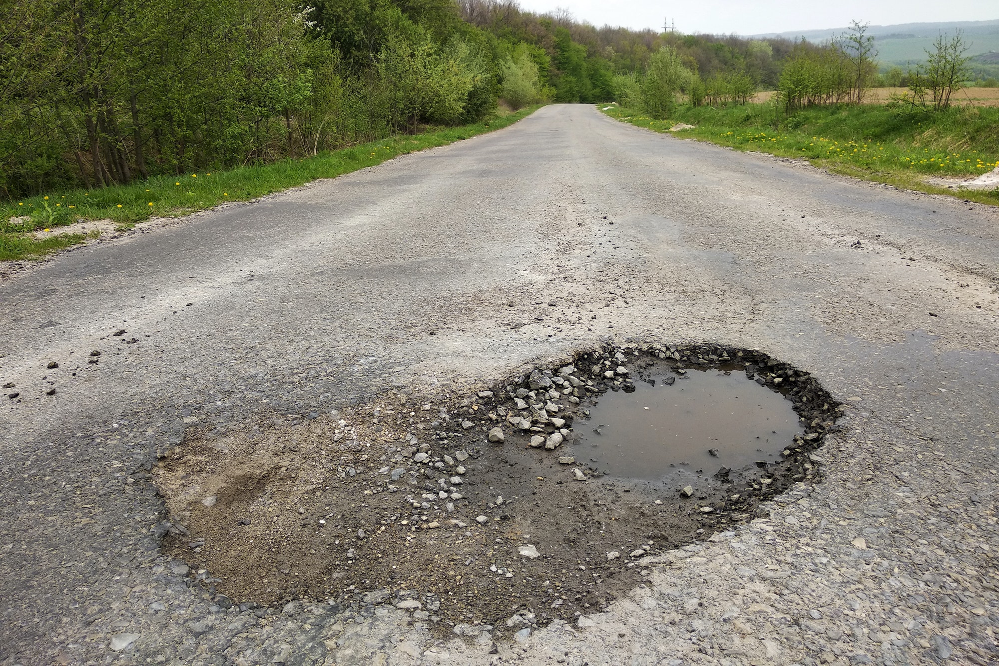 Close up of big pothole with dirty rain water of the road
