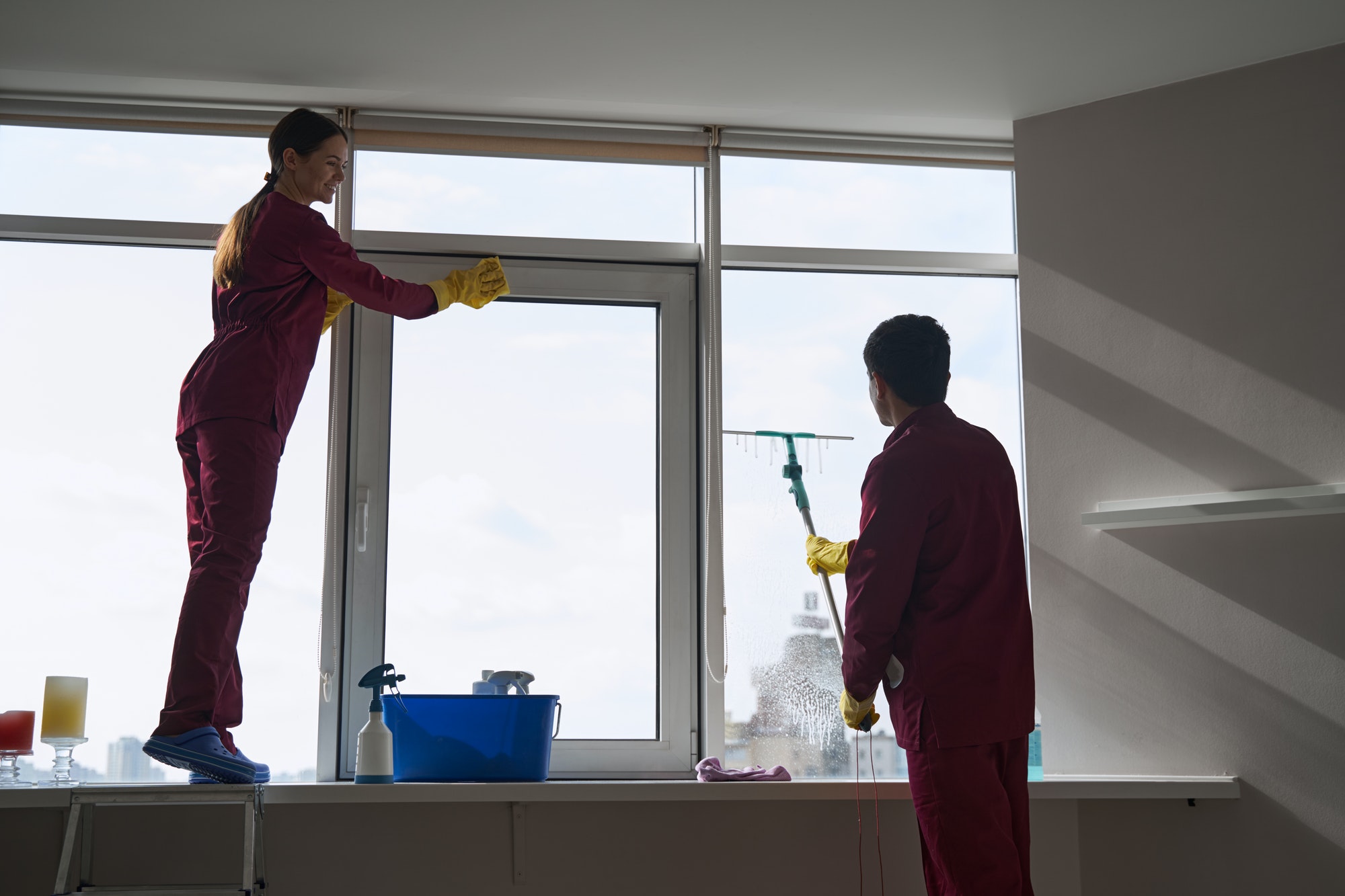 Janitorial staff using microfiber cloth and squeegee for window washing