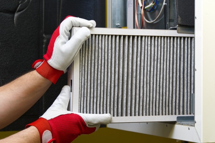 A technician removes an HVAC filter from its housing.
