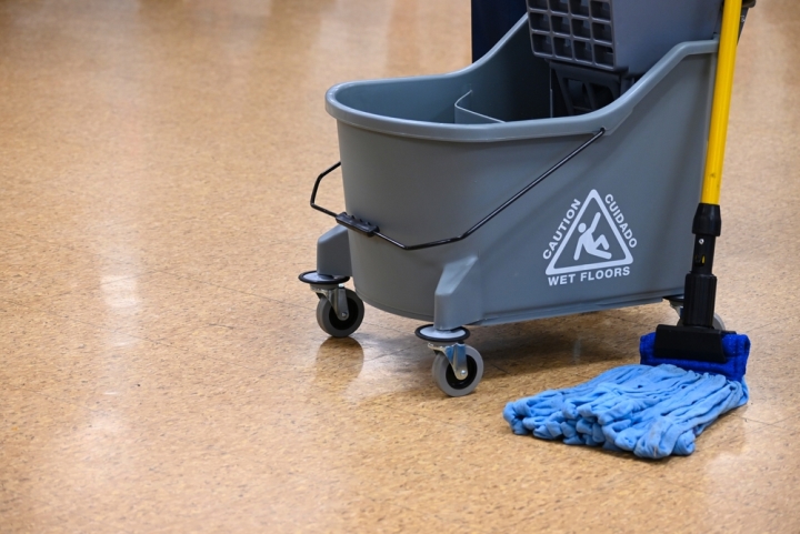 A mop and bucket rest on a school floor.