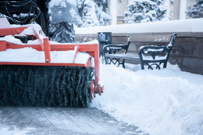 Snowblower cuts path along snow-covered walkway