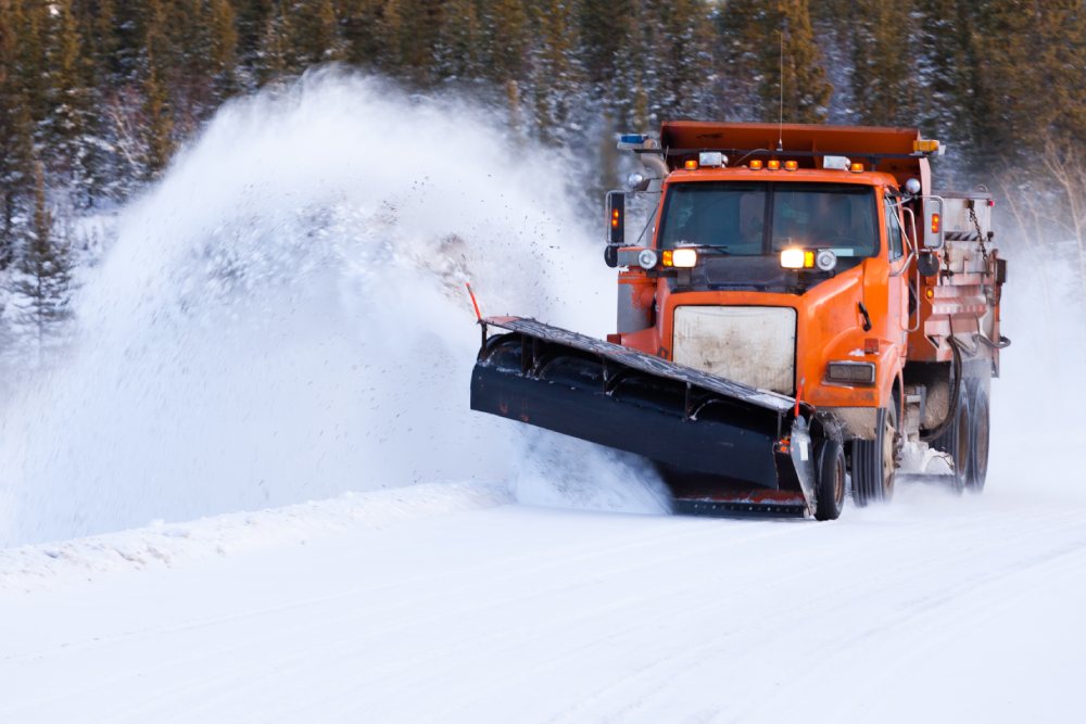 Commercial snow plow service truck clears snowy road